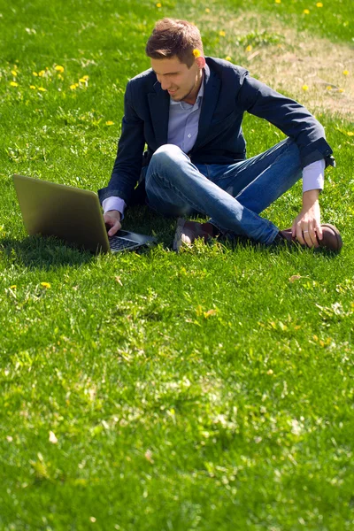 Jonge zakenman op het gras. praten via skype. buiten. — Stockfoto