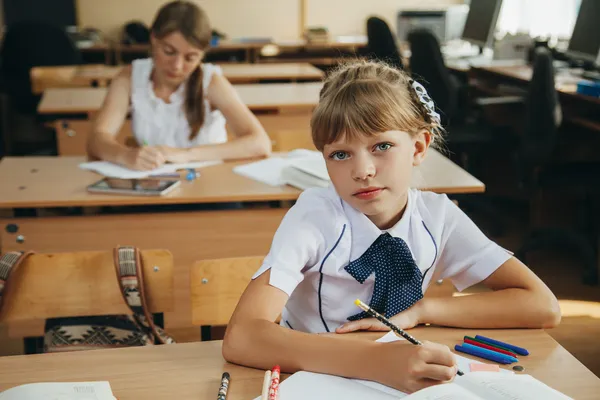 Kleines Mädchen am Schreibtisch schreibt — Stockfoto