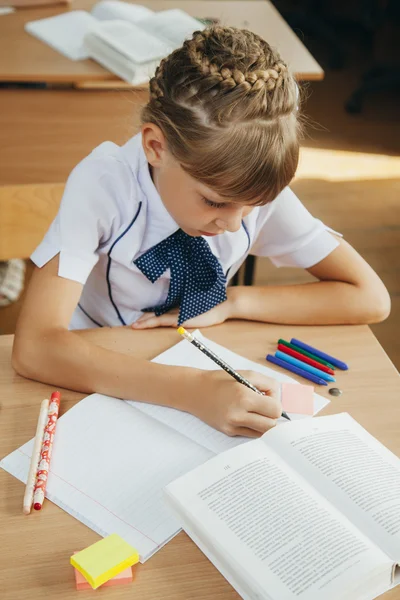 Niña en el escritorio está escribiendo — Foto de Stock