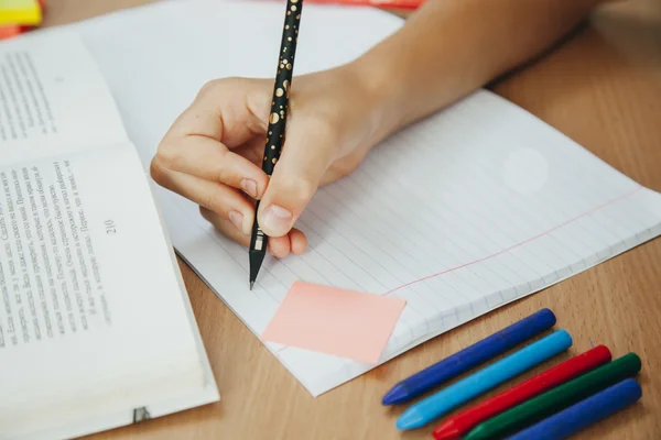 Niña en el escritorio está escribiendo — Foto de Stock