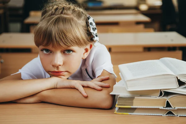 Pequeña estudiante sonriente con muchos libros en la escuela —  Fotos de Stock