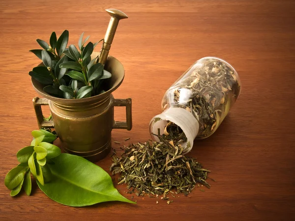 Mortar and pharmacy bottle, with herbs — Stock Photo, Image