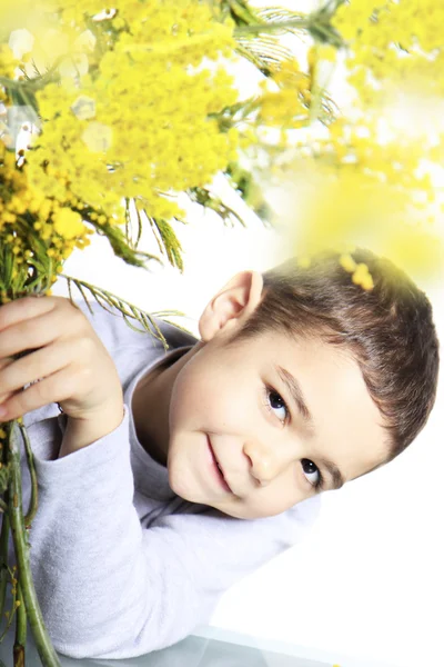 Smiling baby with mimosa flowers — Stock Photo, Image