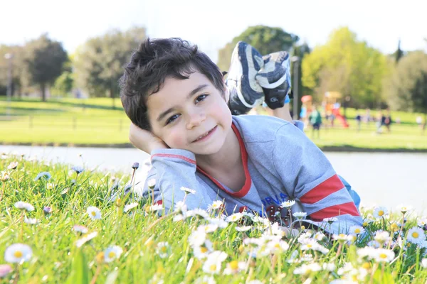 Mutlu çocuk yeşil çim üzerinde yalan — Stok fotoğraf
