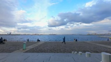 YOKOHAMA, JAPONYA - 7 Kasım 2021: Dramatik bulut oluşumuyla Rinko Park 'ta takılan insanların zaman atlamalı görüntüsü.