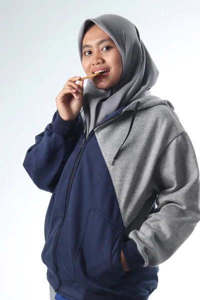 Sıradan kıyafetler giyen Asyalı kadın portresi. Beyaz arka planda gri ceket giyen kapüşonlu bir kadın. Mutlu yüzlü kadınlar bisküvi ya da atıştırmalık yiyor.