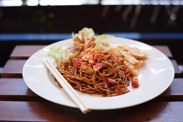 Endonezya 'da çok baharatlı bir tadı olan hazır erişteler. Karışık baharat ve biberli kırmızı erişte. Bulanık arka planda beyaz bir tabakta baharatlı yemekler.