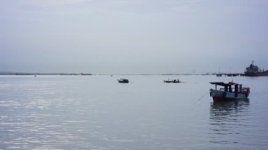 Gresik, Endonezya. Mart 2021 'de balıkçı teknesi petrol rafinerisi şirketinin gemisinden geçiyor.