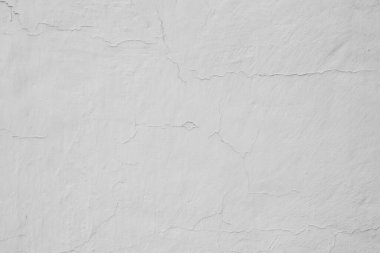 Duvar beyaz boyayla boyanmış, görünür çatlaklarla.