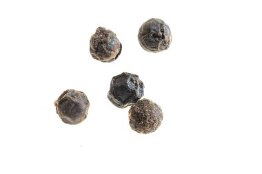 Beyaz zemin üzerinde görünür bir dokusu olan siyah biberler.