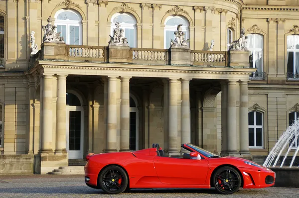 Um carro esportivo vermelho de Maranello em frente ao New Castle Stuttgart - Neues Schloss Stuttgart — Fotografia de Stock