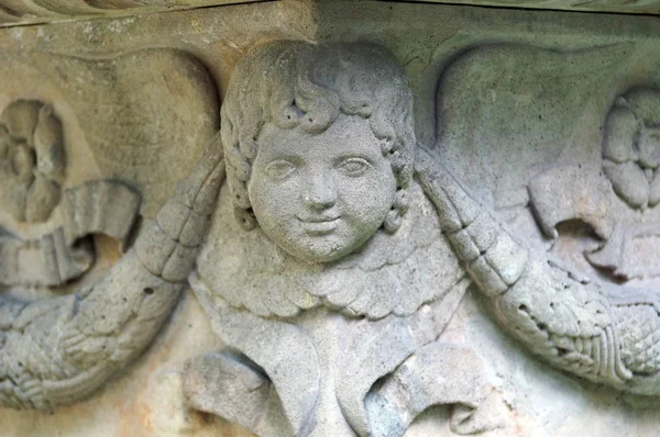 Uma pequena cabeça de anjo na esquina de uma lápide — Fotografia de Stock