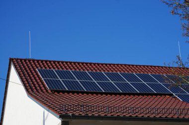 Güneş panelleri güneş ışığında çatıda. Mavi gökyüzü ile, ilkbaharda çok elektrik üretilebilir. Çatı solda ve sağda yüksek paratoner ile korunuyor.