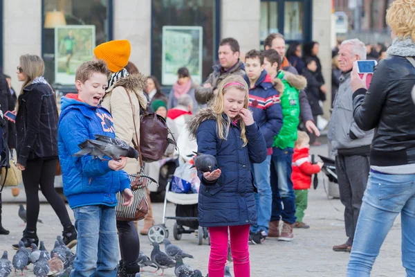 Kinderen voeden van de duiven op Dam in amsterdam — Stockfoto