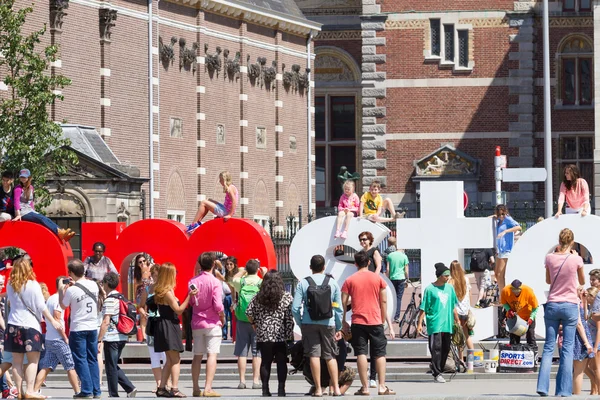 Туристы позируют для логотипа IAmsterdam — стоковое фото