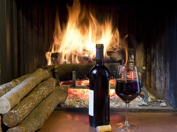 a glass of wine in front of a fireplace
