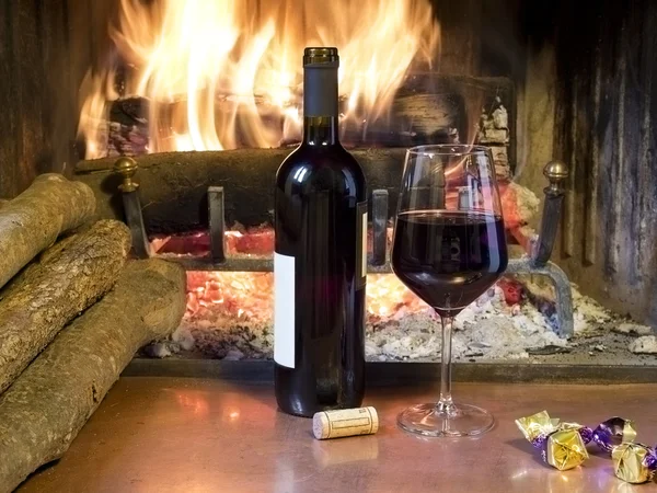 A glass of wine in front of a fireplace — Stock Photo, Image