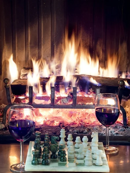 Play chess drinking red wine in front of roaring fireplace — Stock Photo, Image