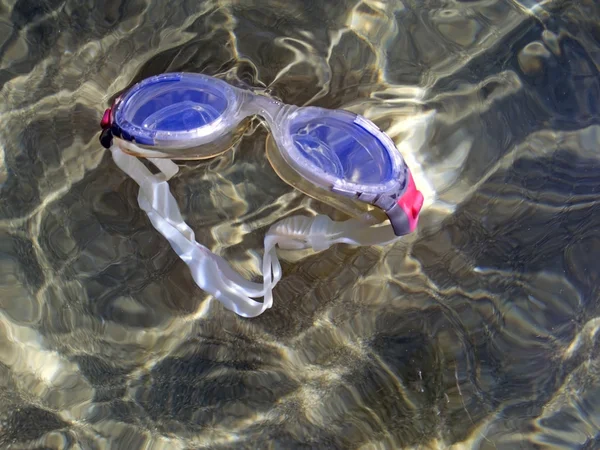 Óculos de natação flutuando na costa, no mar — Fotografia de Stock