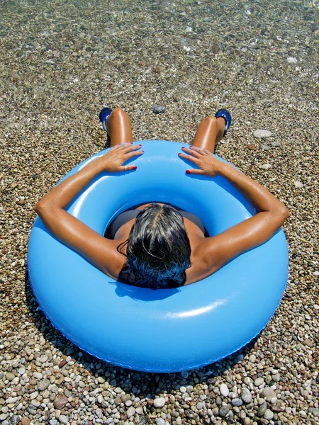 Banho de sol da mulher na costa do mar em um donut inflável — Fotografia de Stock