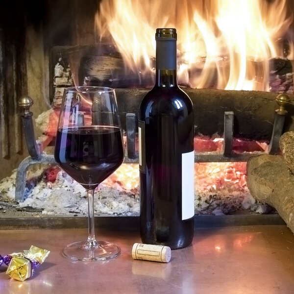 a glass of wine in front of a fireplace