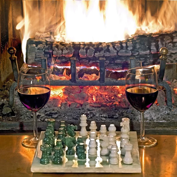 Play chess drinking red wine in front of a roaring fireplace — Zdjęcie stockowe