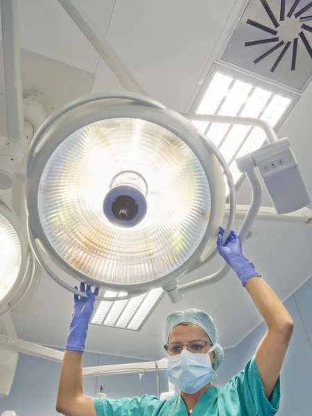 Krankenschwester stellt Chirurgenlampe auf den Operationstisch — Stockfoto