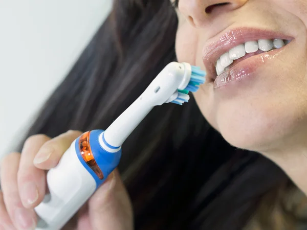 Morena mulher escovar os dentes com escova de dentes elétrica — Fotografia de Stock