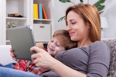 Anne ve oğlu tablet kullanarak gülümseyen