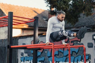 Mahalledeki paralel barlarda karın kası yapan yakışıklı bir adam.