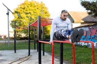 Paralel barlarda ön karın kasları için spor, konsept üzerinde çalışan genç adam.