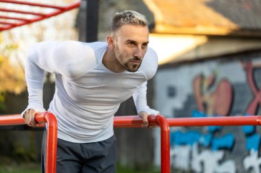 Yakışıklı, kaslı bir adam paralel barlara dalış yaparken egzersizine odaklanmış, egzersiz konsepti dışında.