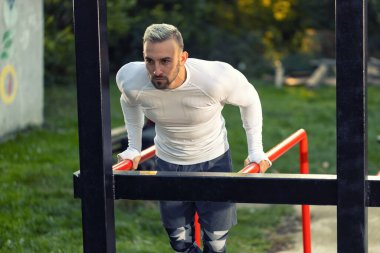 Genç kaslı adam yatay merdiven ve dalış istasyonuna daldırıyor, dışarıda, açık hava sporu konseptinde.