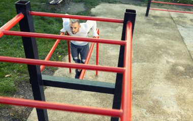 Yakışıklı kaslı genç adam açık gökyüzünün altında çalışıyor, dışarıda egzersiz konsepti var.