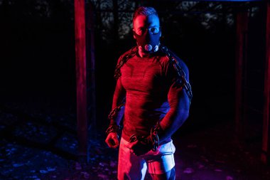 Spor maskesiyle güçlü kaslı bir atlet ve halter zincirleriyle parkta gece boyunca vücut eğitimi, fonksiyonel egzersiz, mahalle konseptinde sokak çalışması