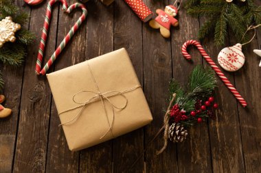Noel hediyesi olarak, Noel süsü, şeker kamışı ve Noel kurabiyeleriyle birlikte ahşap bir masaya konan eko kâğıdı hediye. Mutlu Noeller konsepti.