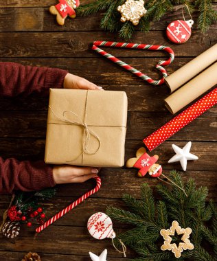 Noel hediyesi olarak ahşap arka planda, kurabiyelerin yanında kış bayramı kurabiyeleri, şeker kamışı, kar tanesi, zencefilli Noel Baba, aile ve aşk konsepti bulunmakta.