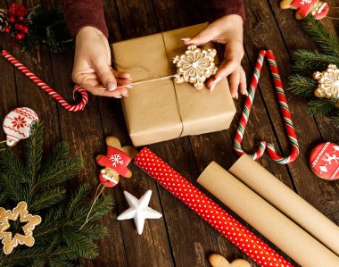 Kar tanesi şeklindeki kış tatili kurabiyesini elinde tutan kadın Noel hediyesi olarak ahşap masa arkasına yerleştirilmiş ve her zaman yeşil dalları olan şekerleme, sevgi, huzur ve aile kavramı ile birlikte...