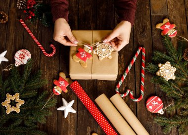 Noel hediyesini, Noel kurabiyeleri ve bisküvilerle süsleyip ahşap masa üzerinde her zaman yeşil dalları ve diğer yılbaşı süsleri olan şenlikli şeker kreması ve bayram hediyesi konseptiyle düzenlemek.