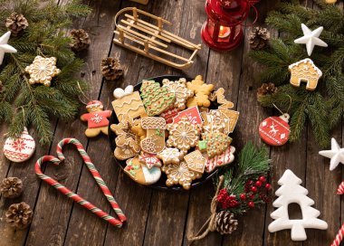 Kurabiyeler, şekerler ve bisküviler Noel süsü ve süslemeleri olan ahşap bir masaya yerleştirilmiş bir tabağa yerleştirilmiş şenlikli kış tatili şekilleri, kış tatili konsepti