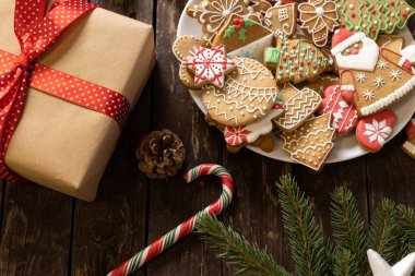 Noel ve Yeni Yıl temalı kırsal ahşap masa, paketlenmiş hediye kutusu, şeker kaplı kış tatili motifi ev yapımı zencefilli kurabiye ve bisküvi, şeker kamışı, yemyeşil dallar, tatil masası konsepti.