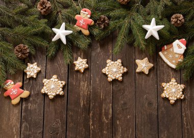 Yıldız ve kar tanesi şekilli zencefilli Noel kurabiyeleri kozalaklı kozalaklara ve ahşap arka plan konseptine yerleştirilmiş krema.