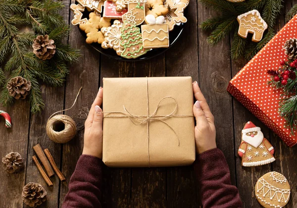 Memegang Hadiah Natal Atas Meja Kayu Yang Dihiasi Dengan Kue — Stok Foto