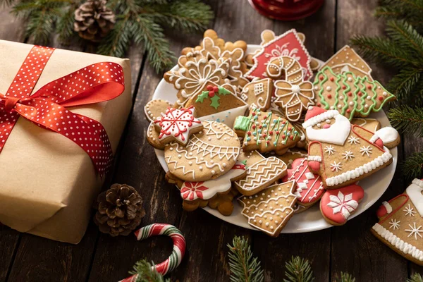 Noel kurabiyeleri, bayram temalı şenlikli Noel kurabiyeleri ve kırsal ahşap masaya konmuş hediye paketi, tatil konsepti.