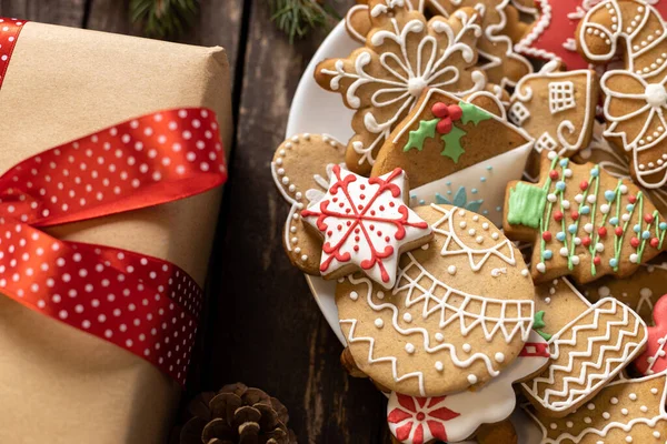 Noel kurabiyeleri, bayram temalı şenlikli Noel kurabiyeleri ve kırsal ahşap masaya konmuş hediye paketi, tatil konsepti.