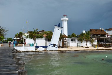 Puerto Morelos 'ta, Meksika' daki Yucatan Yarımadası 'ndaki Malecon ahşap iskelesinde eğilmiş Faro Inclinado deniz feneri..