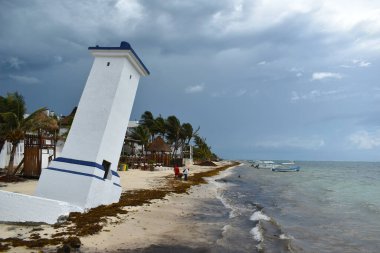 Puerto Morelos 'ta, Meksika' daki Yucatan Yarımadası 'ndaki Malecon ahşap iskelesinde eğilmiş Faro Inclinado deniz feneri..
