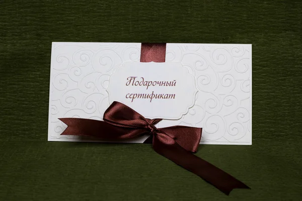 Gift Certificate white with brown ribbon — Stock Photo, Image