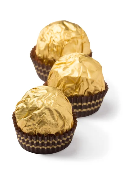 Three isolated chocolate candies in golden foil — Stock Photo, Image