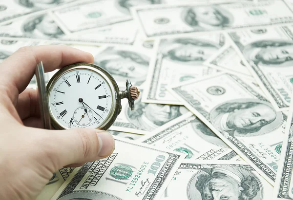 Hand holding watch on dollar banknotes — Stock Photo, Image